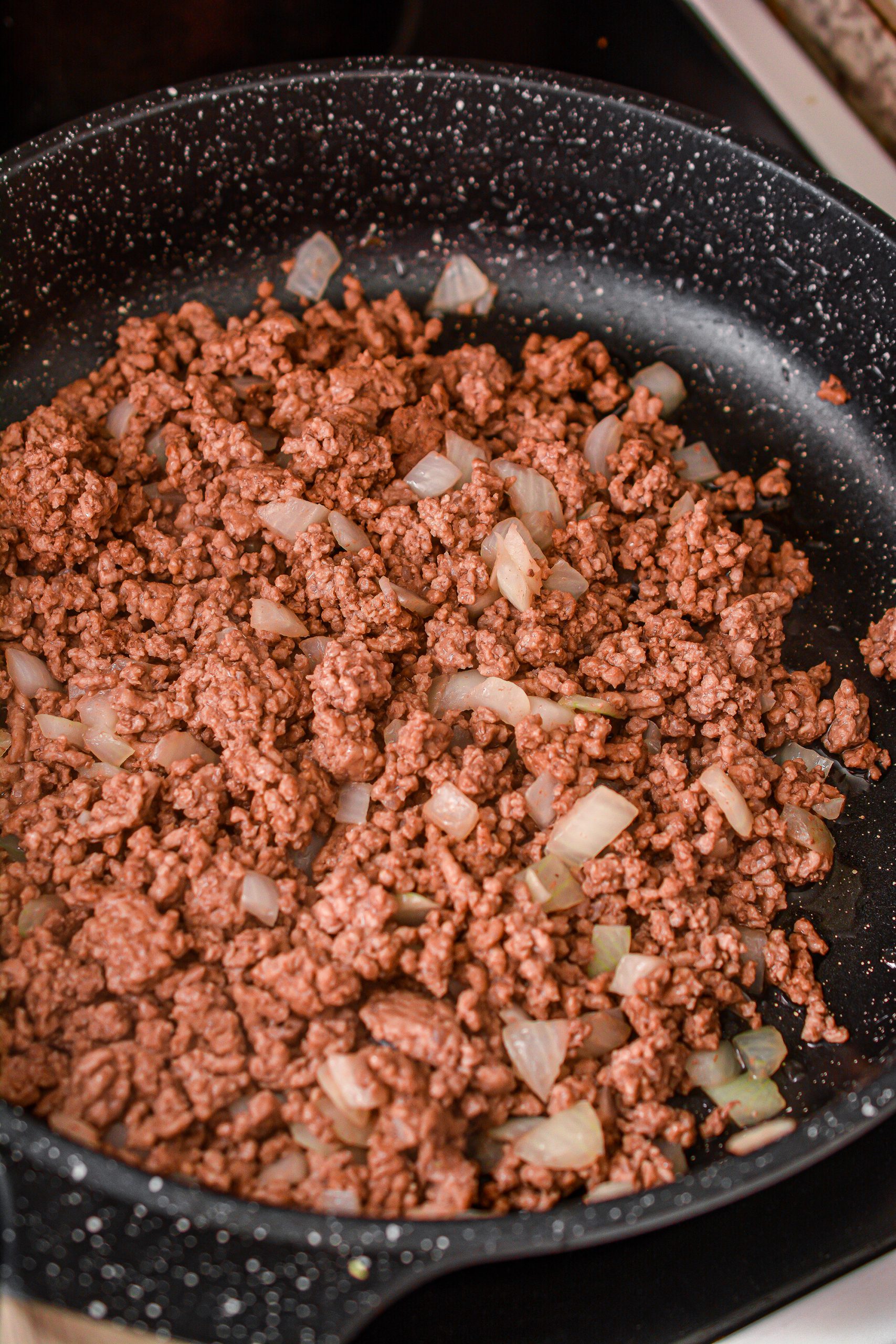Add the ground beef and onions to a skillet over medium-high heat on the stove.