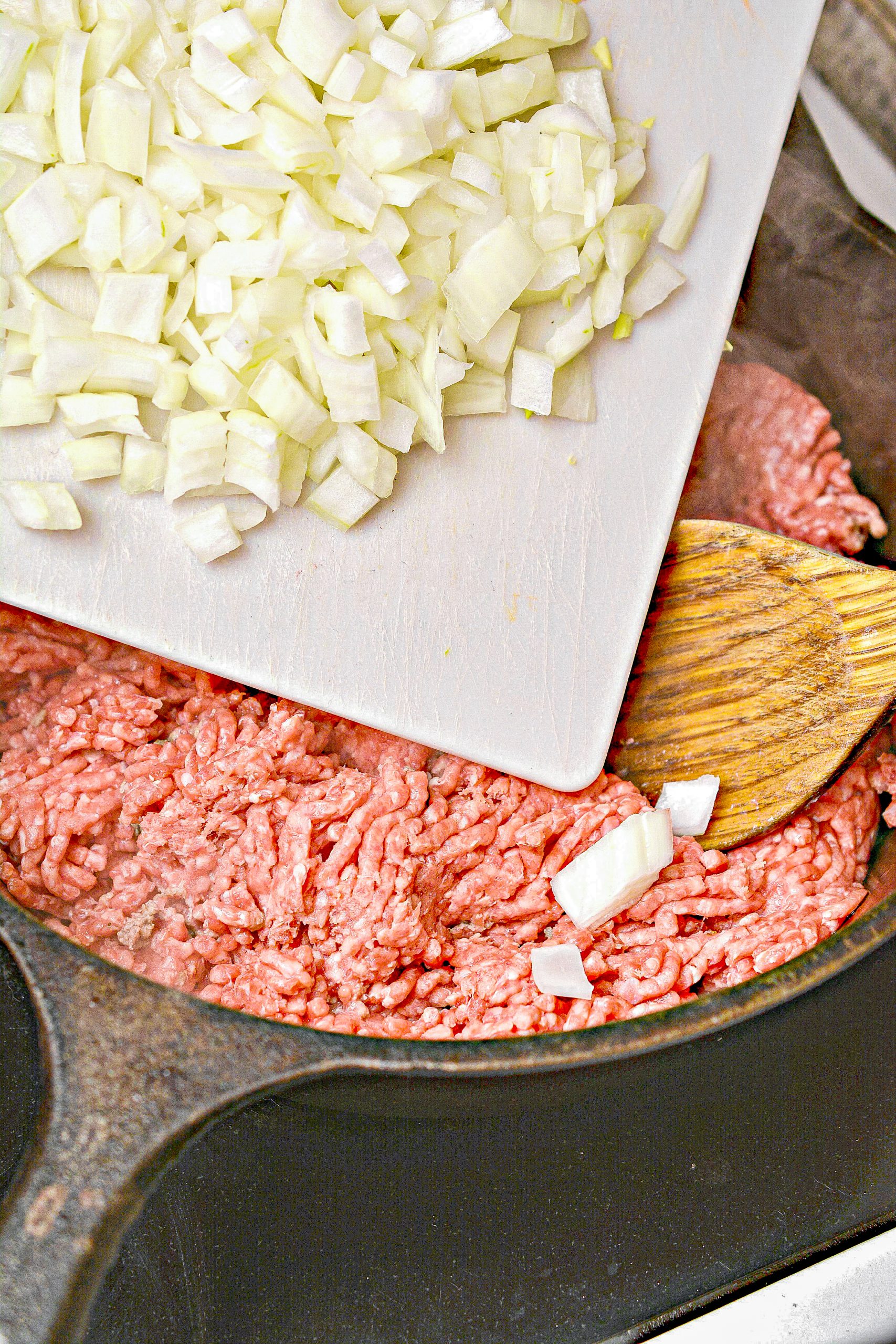 Add the olive oil, ground beef, and onions to the skillet, and saute until the beef is completely browned. Drain any excess fat.