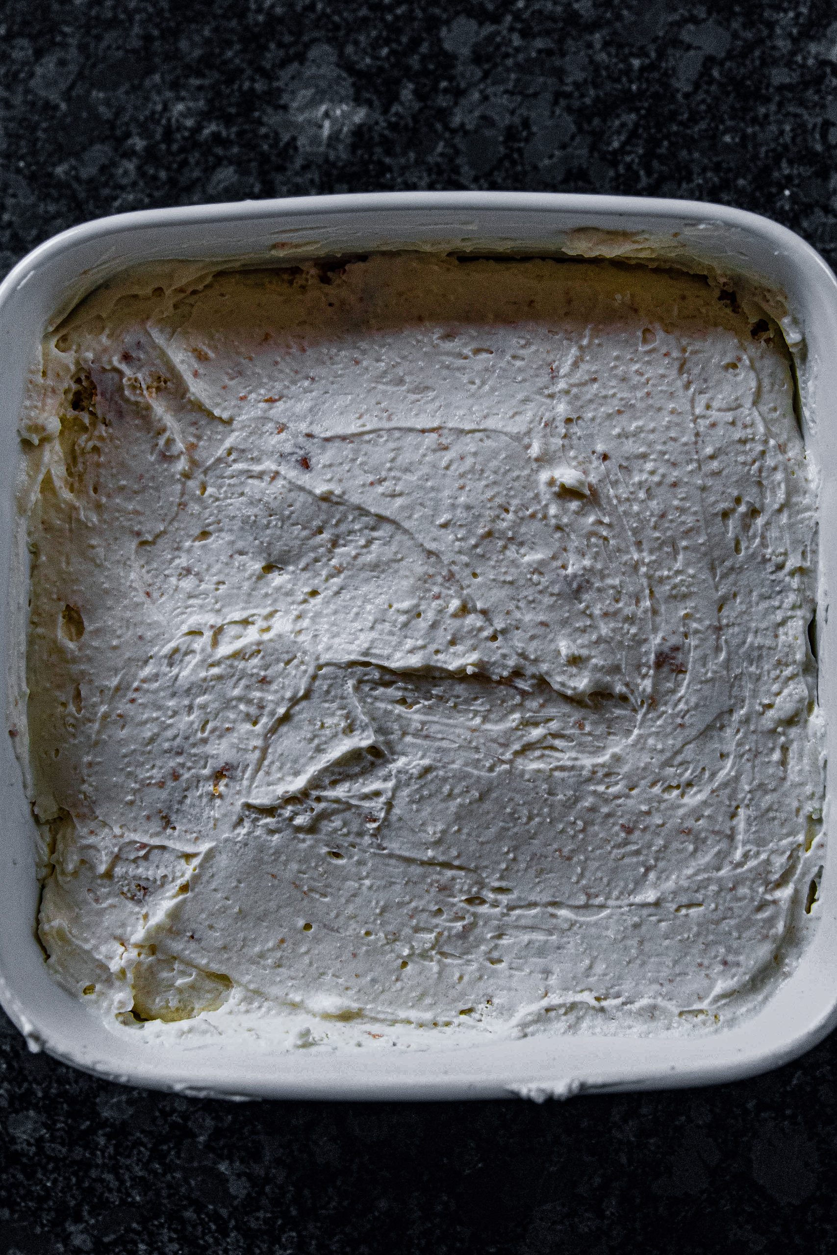 Add your cream cheese mixture  into the crumbled cake and spread it in an even layer on top of the crumbled cake