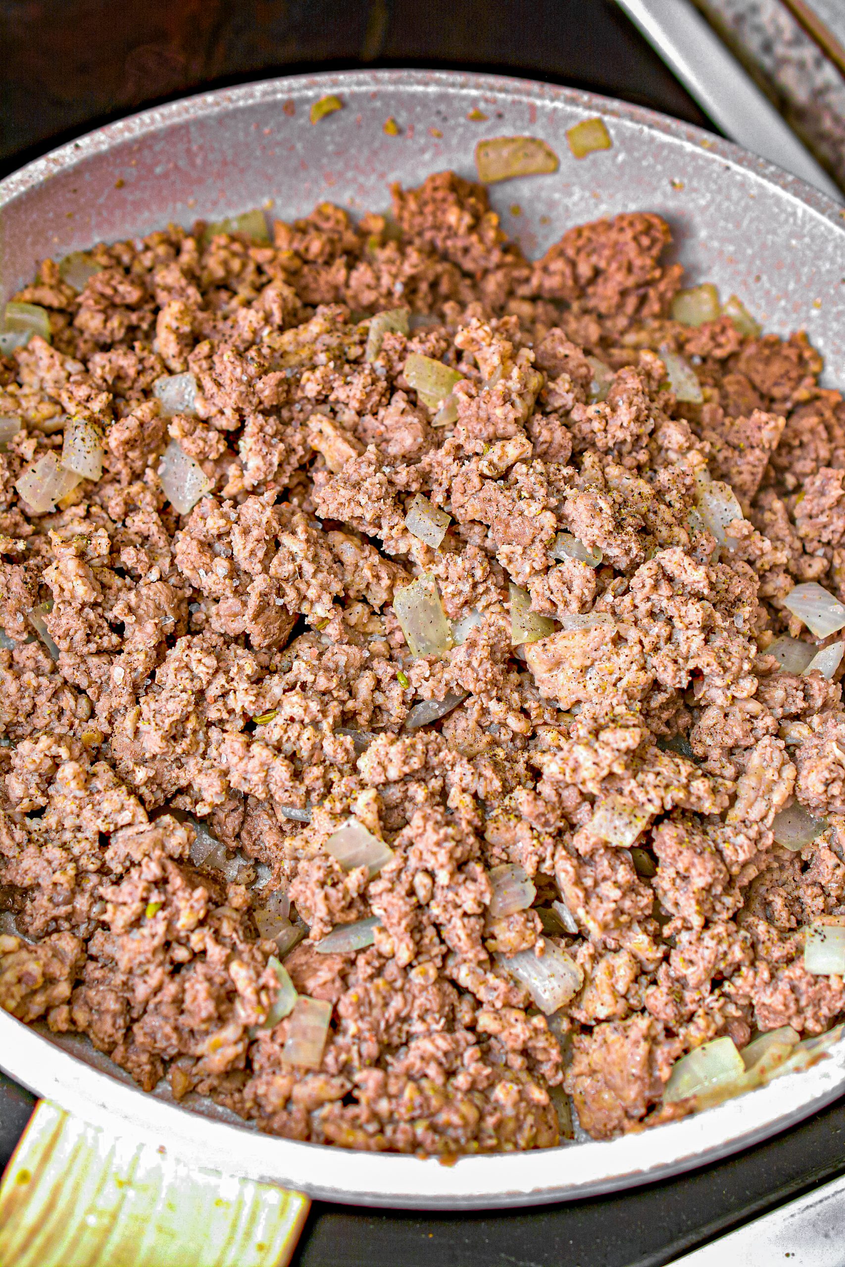Cook the ground beef, onions and ground sausage in a large skillet over medium high heat until the meat is browned completely, and the onions have softened.