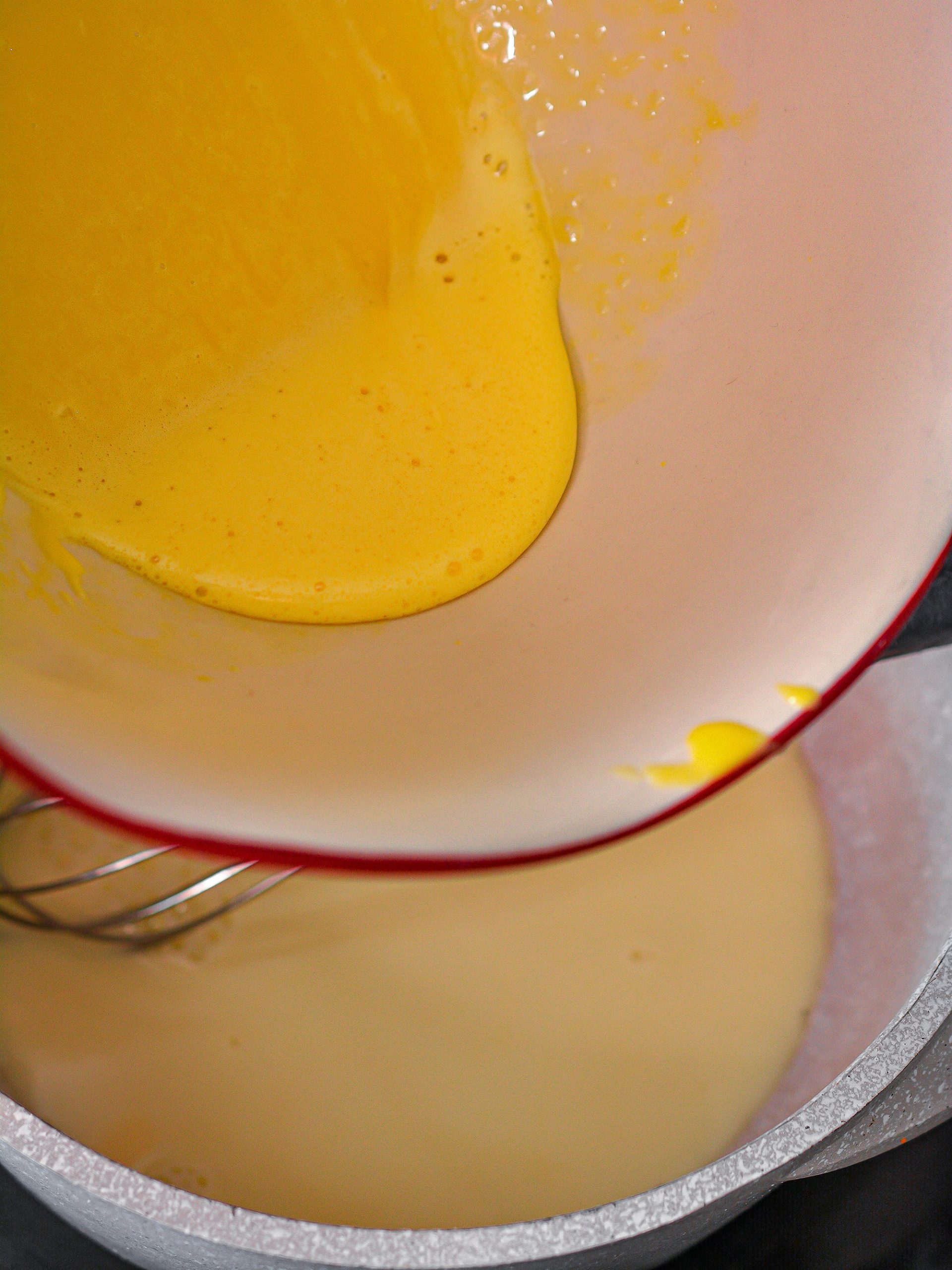 Slowly whisk the egg yolks into the saucepan, mixing continuously.