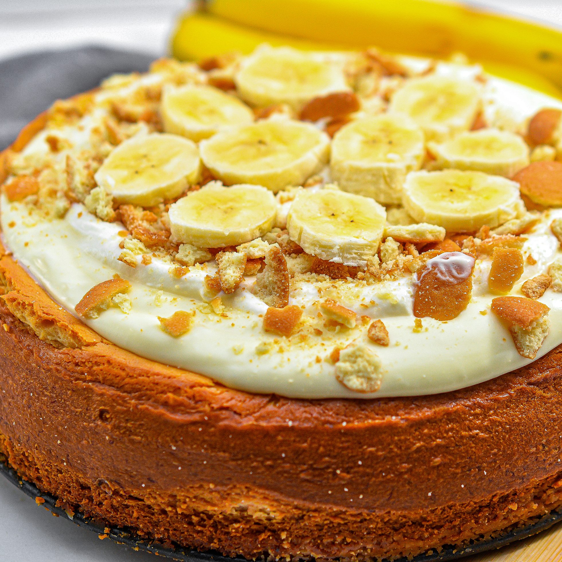 Spread the whipped cream on top of the cheesecake and garnish with crushed vanilla wafers and freshly sliced bananas before serving.