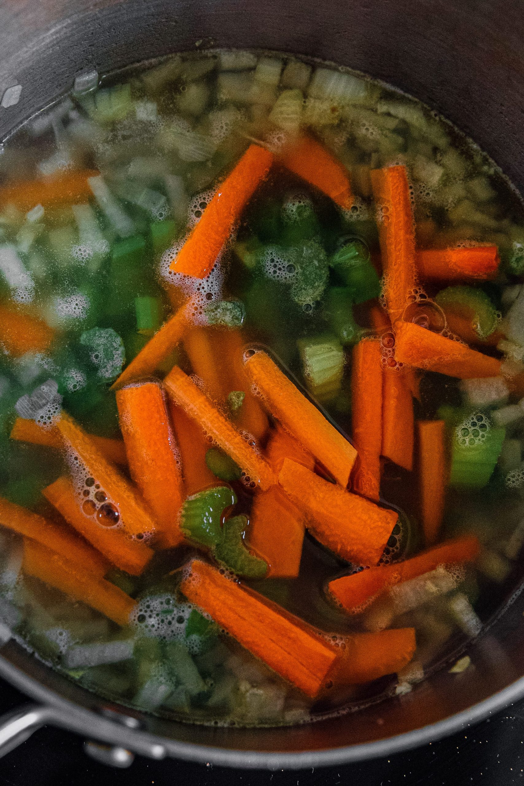 Add the celery and carrots to the pot, followed by the chicken stock. Bring to a boil, then reduce to a simmer.