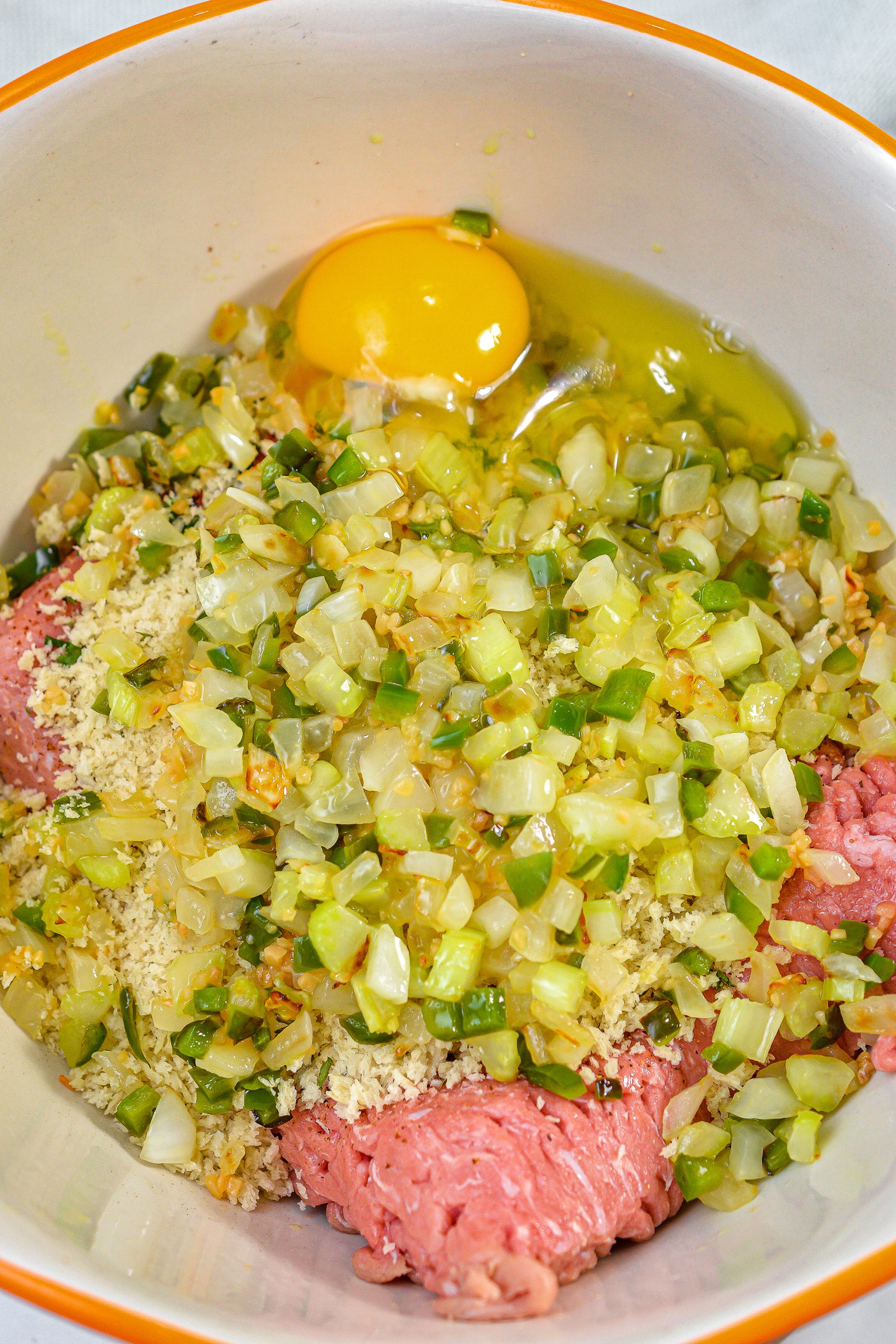Add the cooled vegetables to a large mixing bowl with the ground turkey, cajun seasoning, 1 Tbsp chili flakes, chopped parsley, large egg, panko crumbs and salt and pepper to taste.