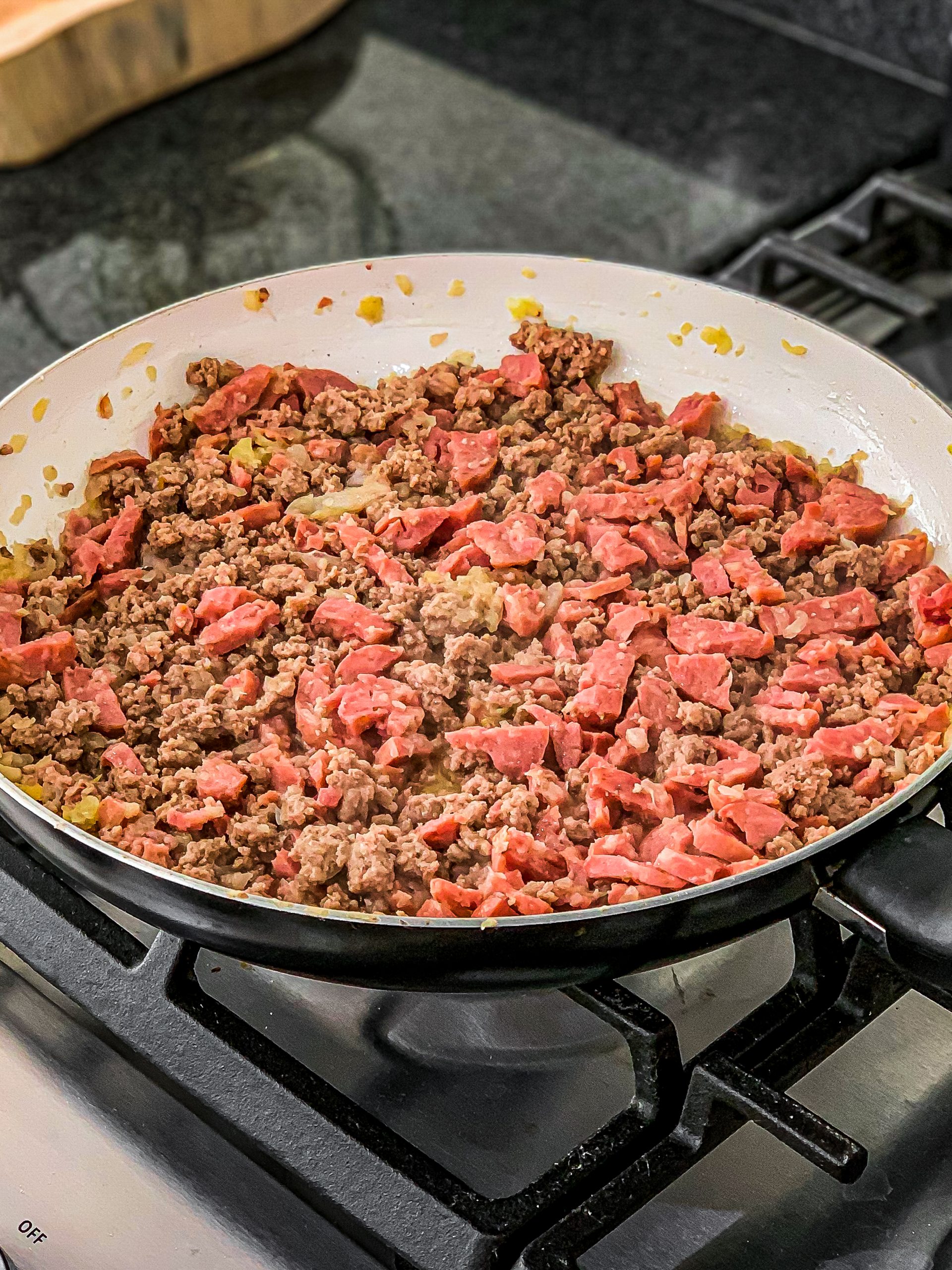 Add the ground beef along with the sausage, and cook until golden brown.