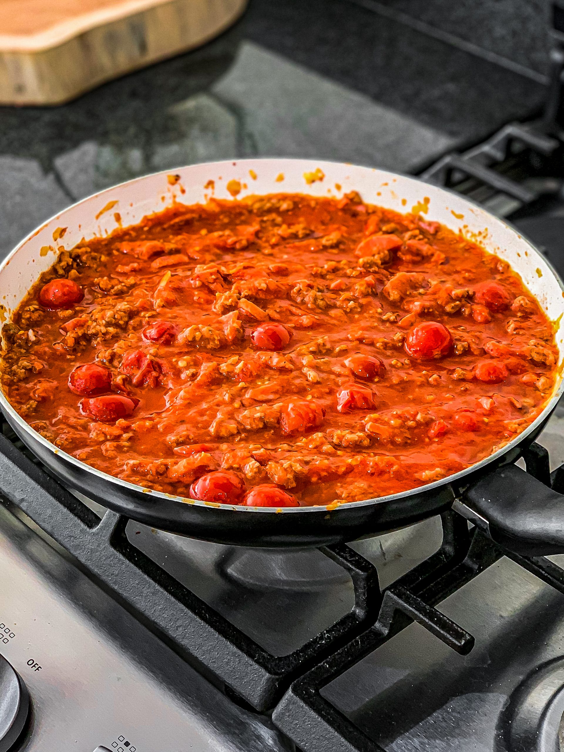 Remove the meat from the pan and add the garlic, the tomatoes in the juice can, and the tomato sauce to it. Stir very well.