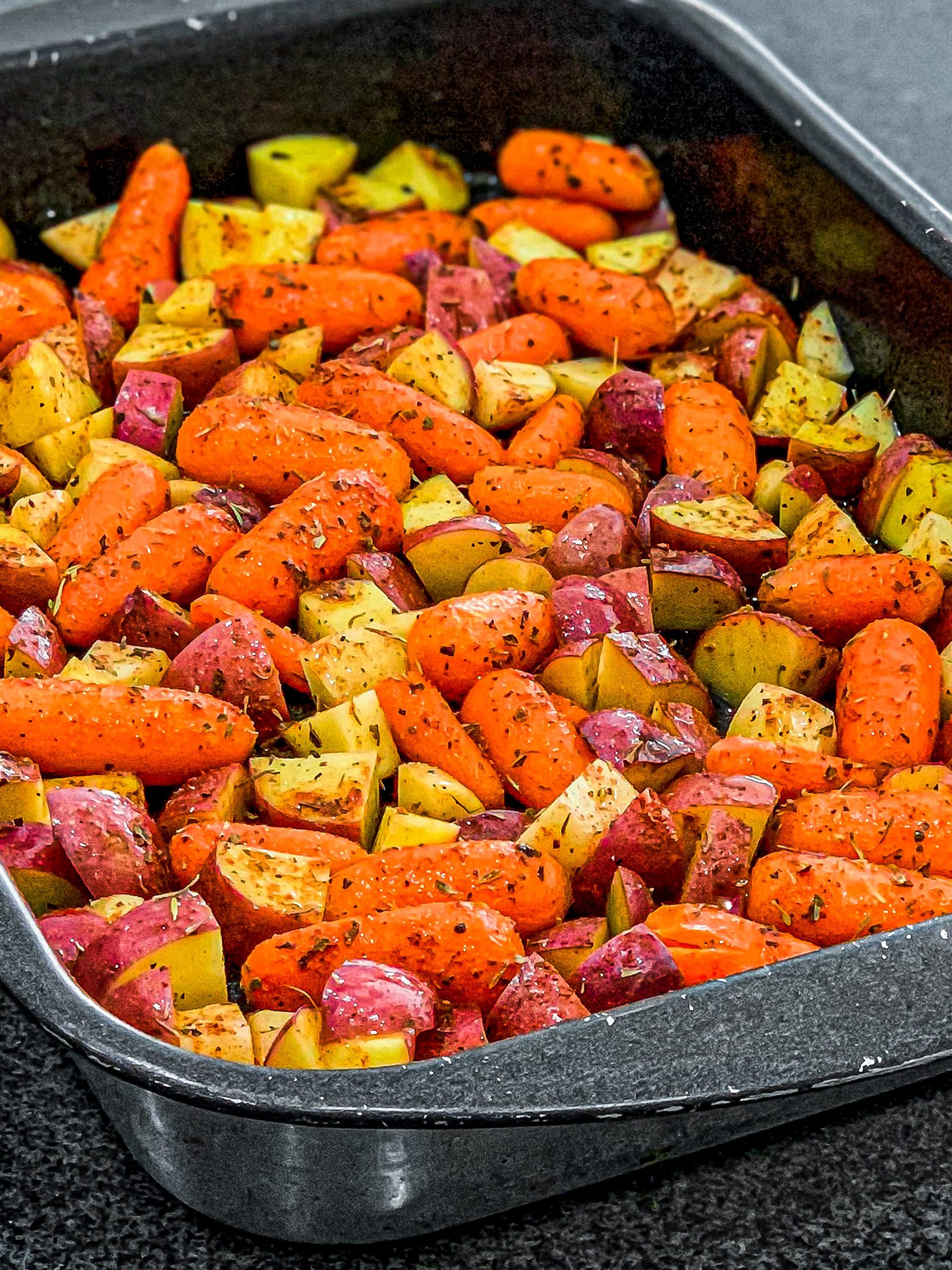 Sprinkle half of the mixed dry herbs over the top of the carrots and potatoes and toss until evenly coated.
