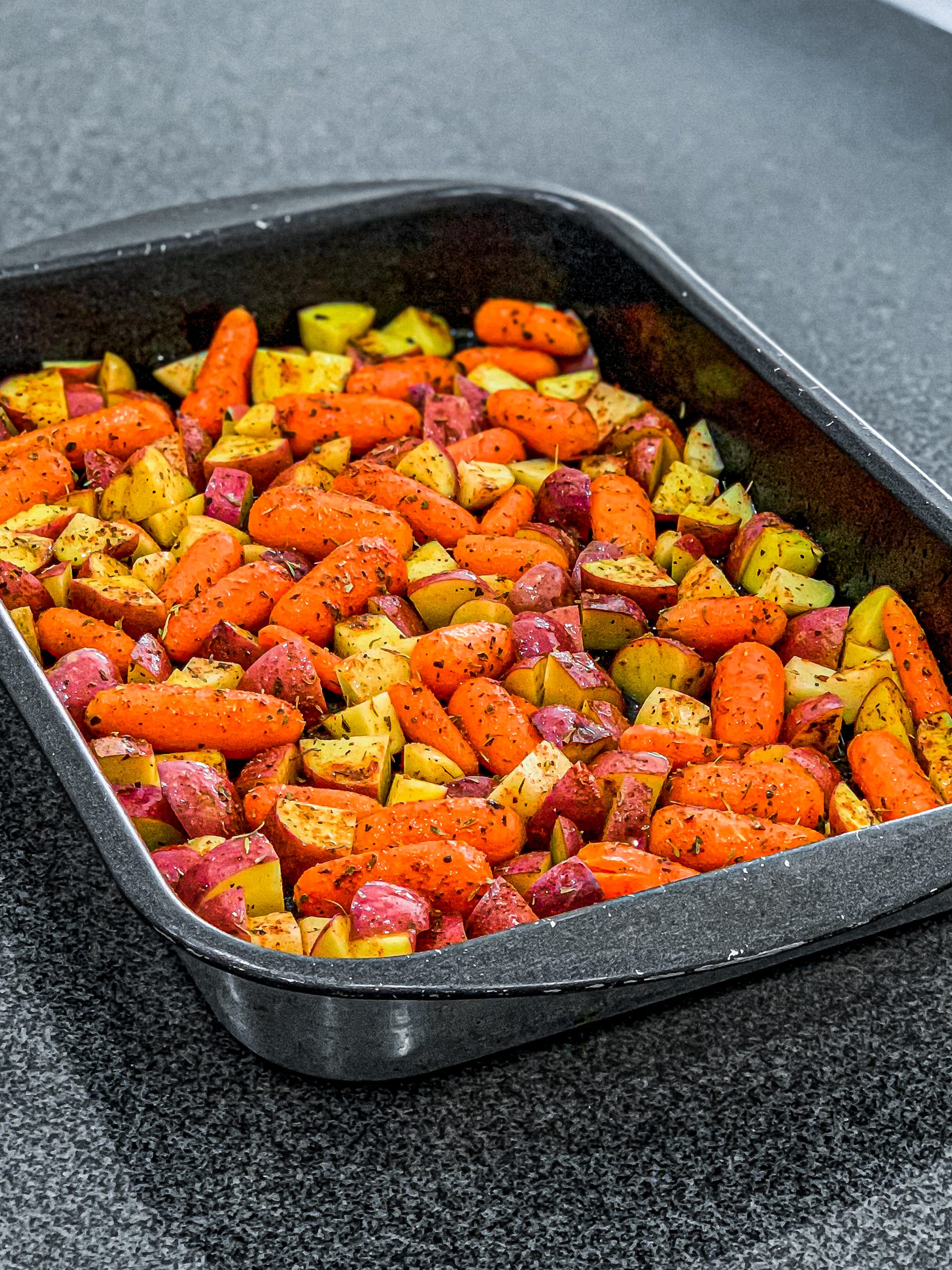Sprinkle half of the mixed dry herbs over the top of the carrots and potatoes and toss until evenly coated.
