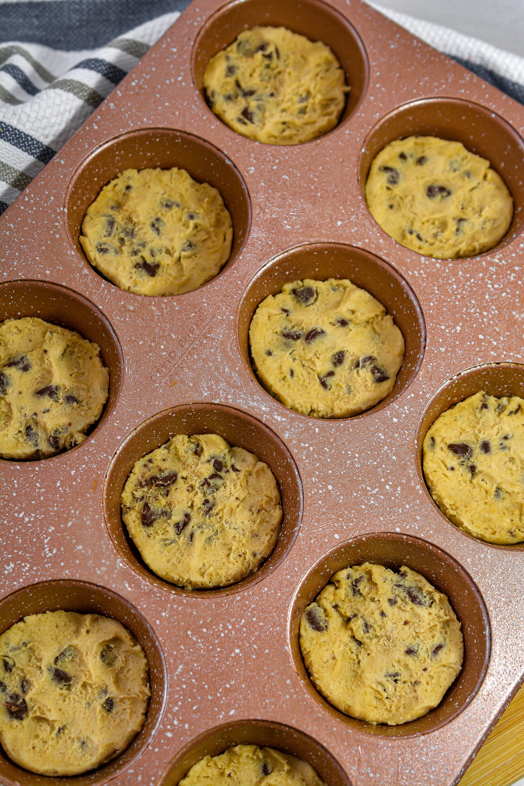 Separate the cookie dough into 12 even sections, and press one section into each of the cups of the muffin tin.
