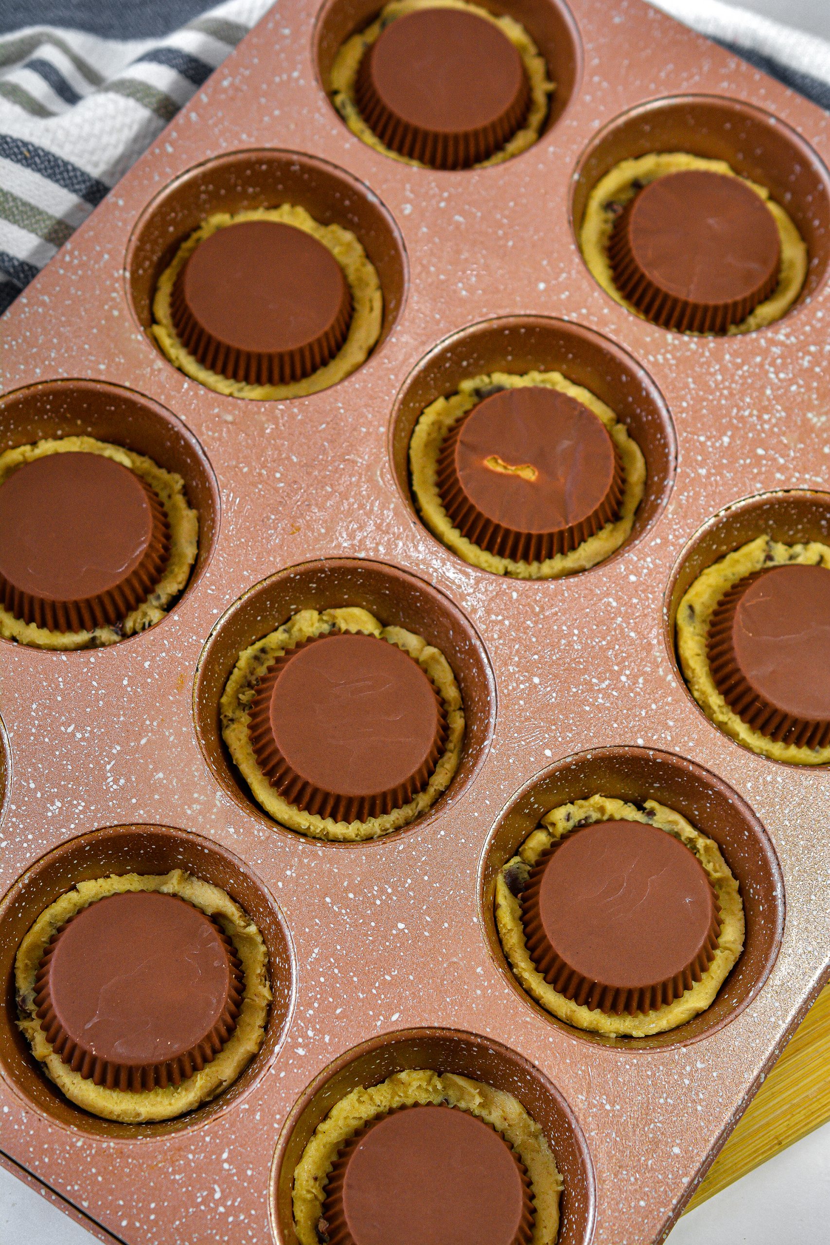 Place a Reese’s peanut butter cup upside down into each of the sections of the muffin tin.