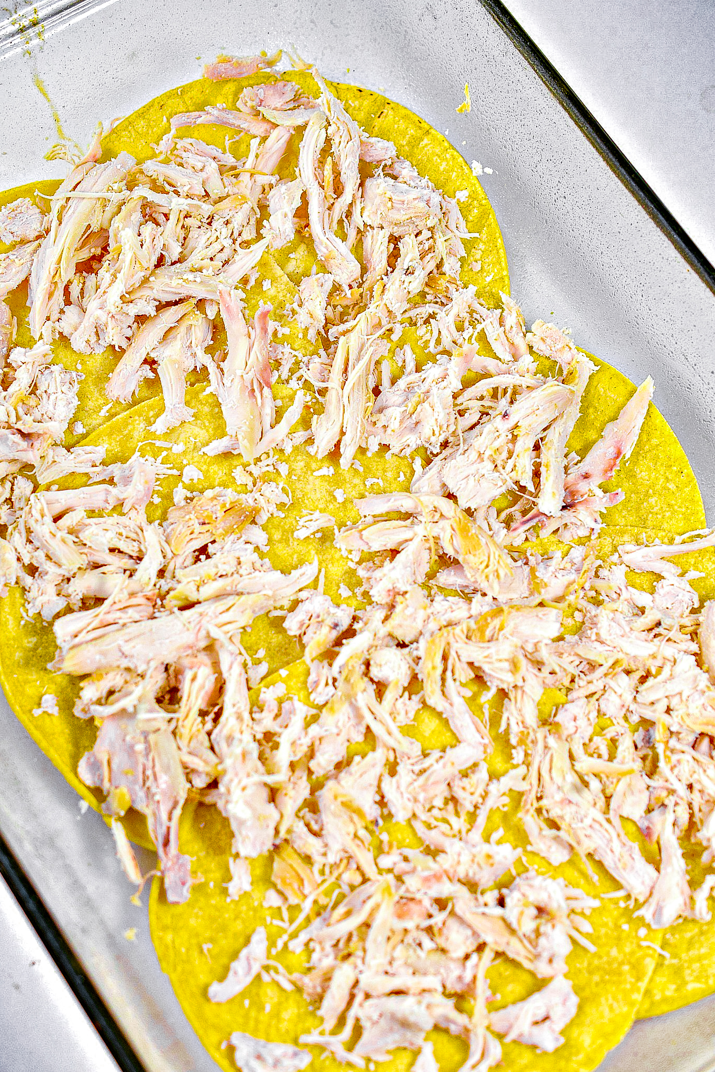 Place ½ of the chicken, then ½ of the sauce mixture, and a sprinkling of cheese in a layer on top of the tortillas.
