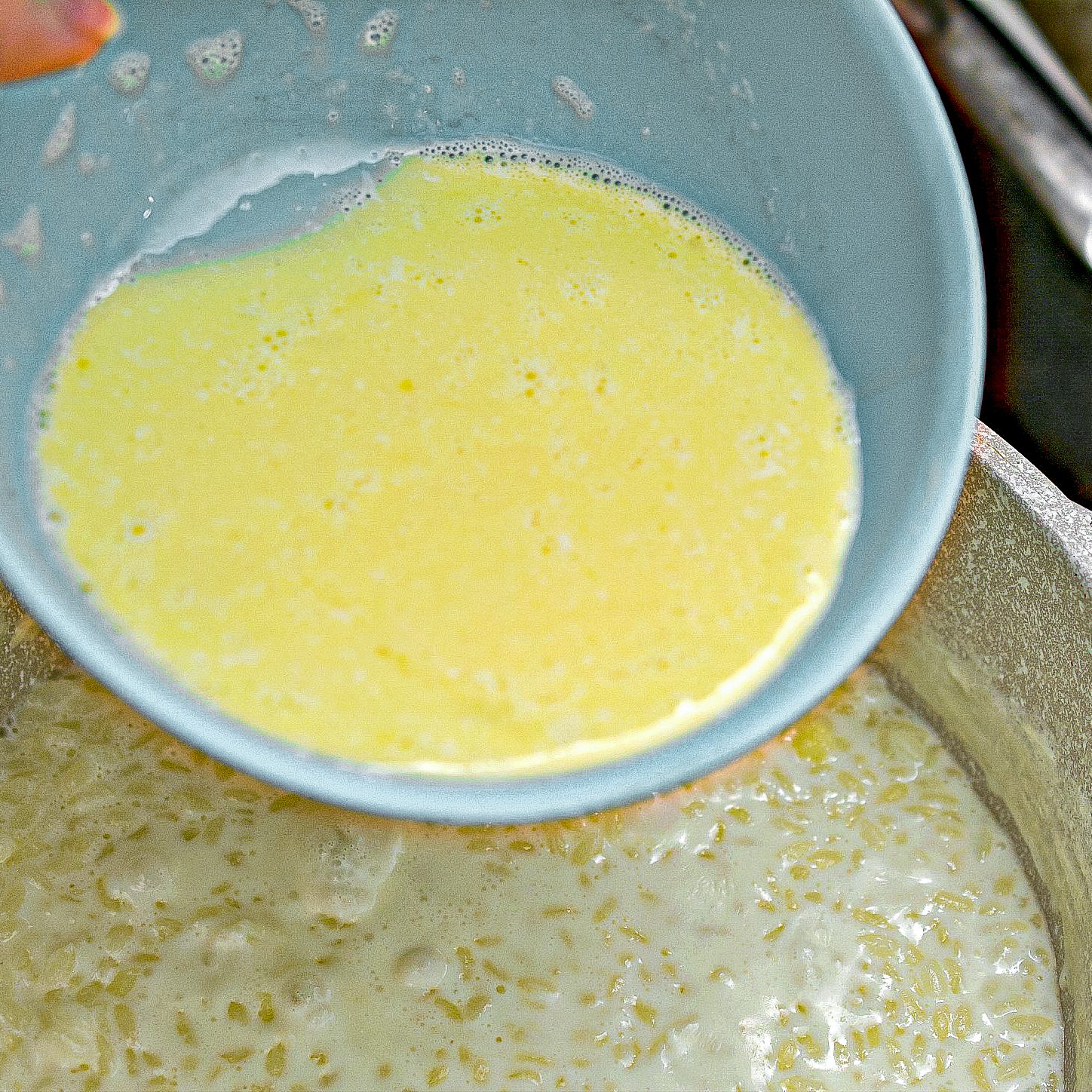 Slowly whisk the tempered egg and milk mixture into the rice pudding.