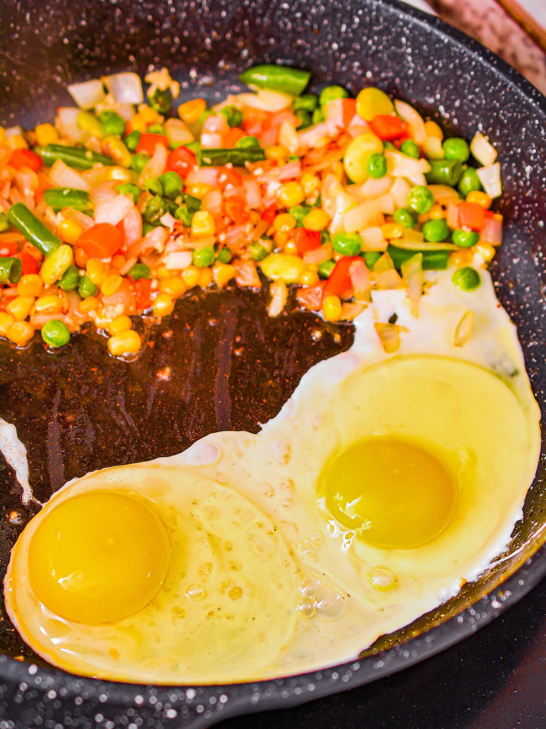 Shove the vegetables to one side of the skillet, and crack the eggs into the skillet. 