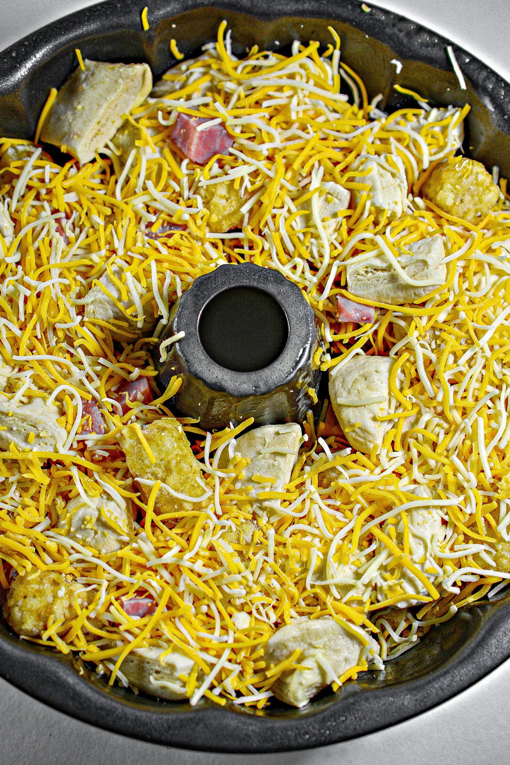 Mix together the ham, tater tots, cheese, and cut up biscuits in a large bowl, and place it into a well-greased bundt pan.