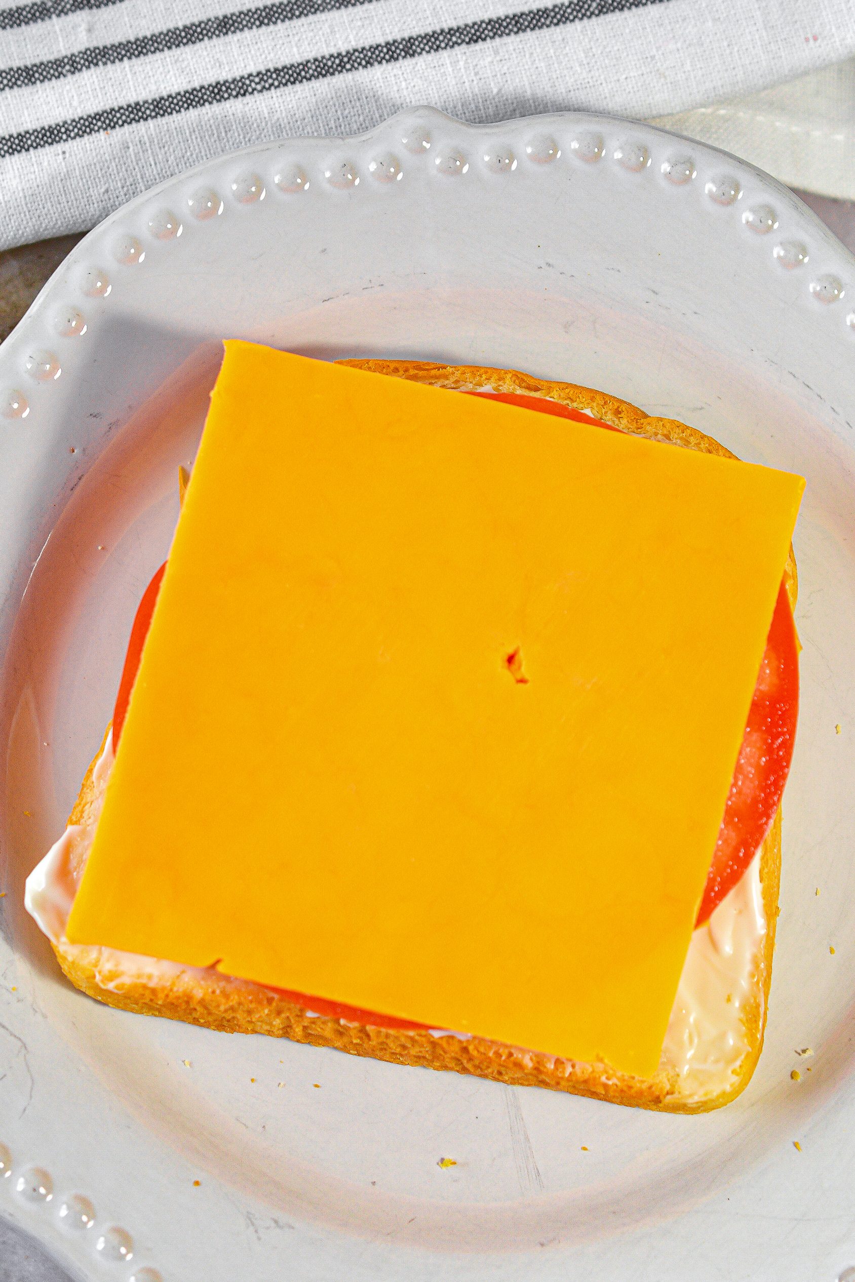 Add a slice of cheese on top of the tomato slices.