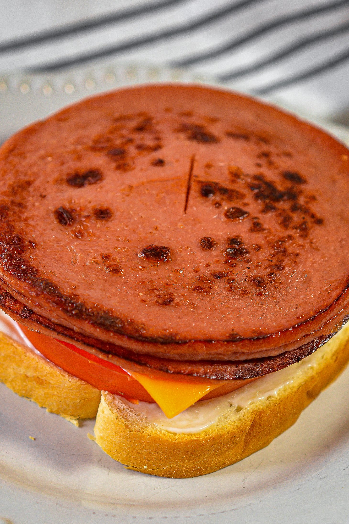 Slice an x through the center of each piece of bologna, and place them into the skillet.